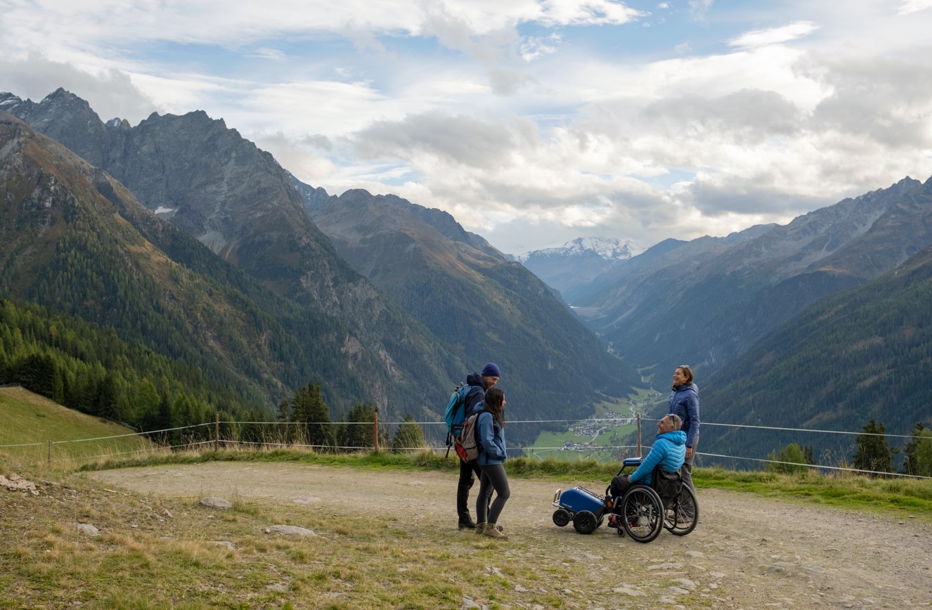 Wandergruppe auf einer Alm mit Bergen im Hingergrund