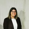 Eine Frau mit langen, glatten Haaren steht vor einer hellen Wand und l&auml;chelt freundlich in die Kamera.