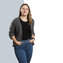Eine Frau mit langen, glatten Haaren tr&auml;gt eine graue Strickjacke &uuml;ber einem schwarzen T-Shirt und steht selbstbewusst da.
