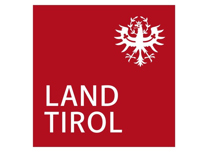 Das Tiroler Wappen pr&auml;sentiert einen wei&szlig;en Adler mit Krone, unter dem der Schriftzug 'LAND TIROL' in klaren Buchstaben steht.