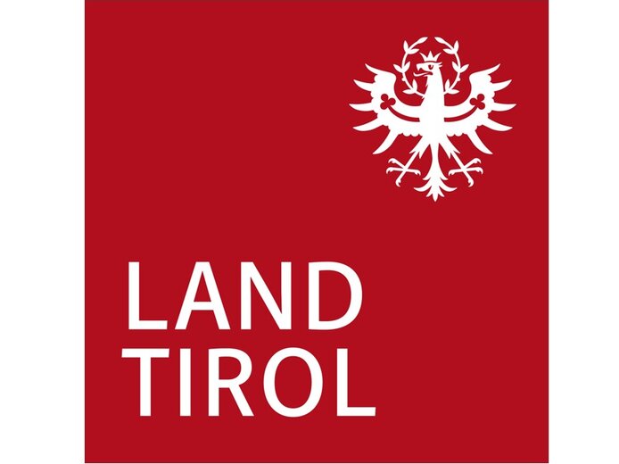 Das Tiroler Wappen pr&auml;sentiert einen wei&szlig;en Adler mit Krone, unter dem der Schriftzug 'LAND TIROL' in klaren Buchstaben steht.