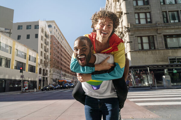 In a vibrant urban setting, a man joyfully carries his friend on his back, both radiating happiness and friendship.