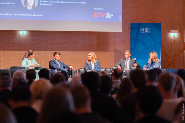 Eine Diskussionsrunde mit vier Personen auf einer Bühne, die über Familienunternehmen sprechen, während das Publikum aufmerksam zuhört.