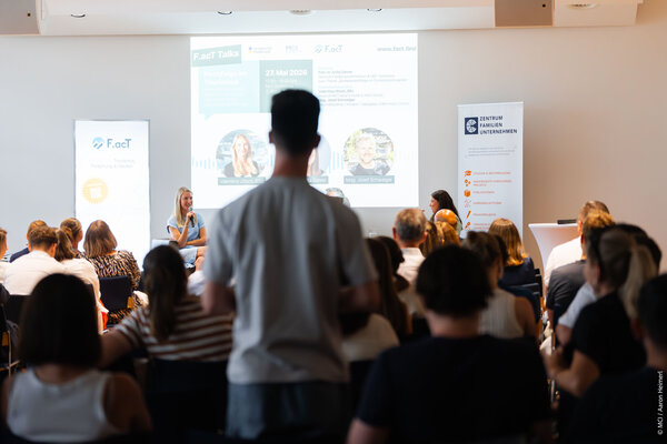 A lively discussion unfolds at a tourism event, highlighting speakers and an engaged crowd in a professional atmosphere.